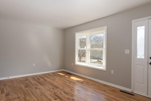 foyer featuring visible vents, baseboards, and wood finished floors