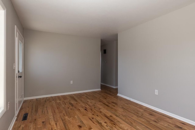 empty room featuring visible vents, baseboards, and wood finished floors