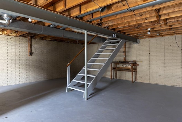 unfinished basement with stairs and brick wall