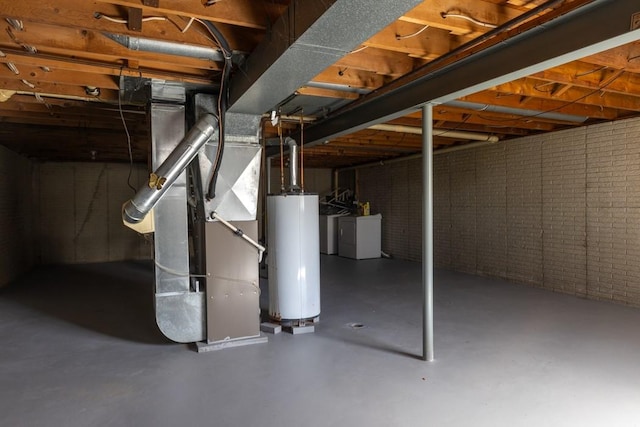 unfinished basement with washing machine and dryer, gas water heater, and brick wall