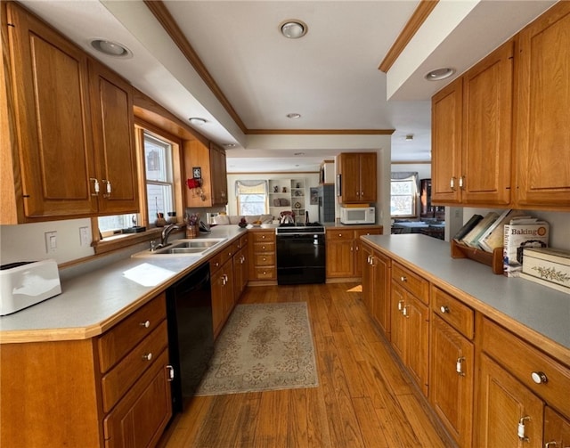 kitchen with black appliances, crown molding, brown cabinets, and a sink