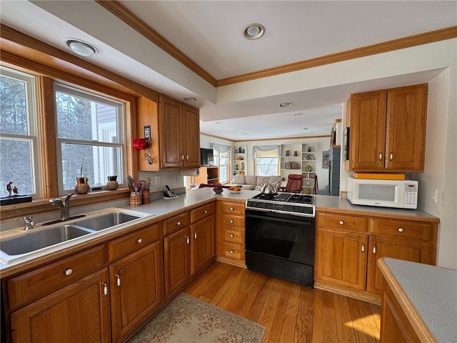 kitchen featuring brown cabinetry, gas stove, a sink, and white microwave