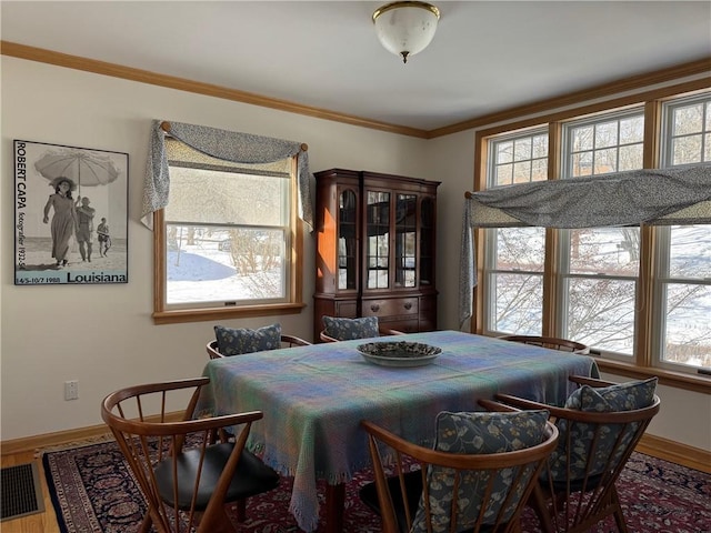 dining room with baseboards, wood finished floors, and crown molding