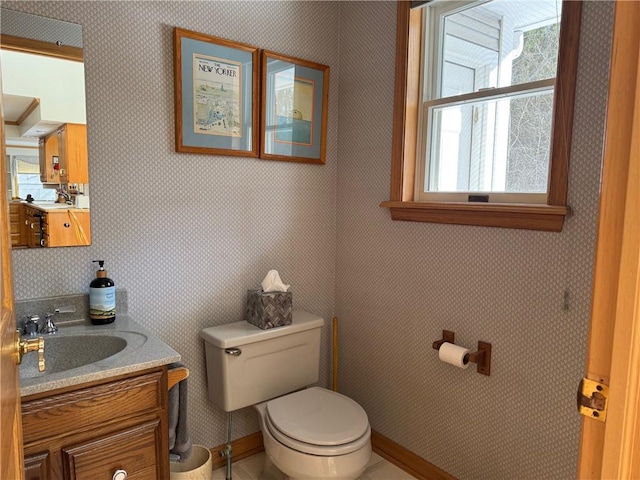 half bath featuring baseboards, vanity, toilet, and wallpapered walls