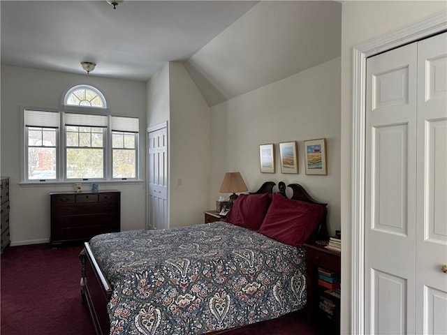 bedroom featuring lofted ceiling, dark carpet, and baseboards