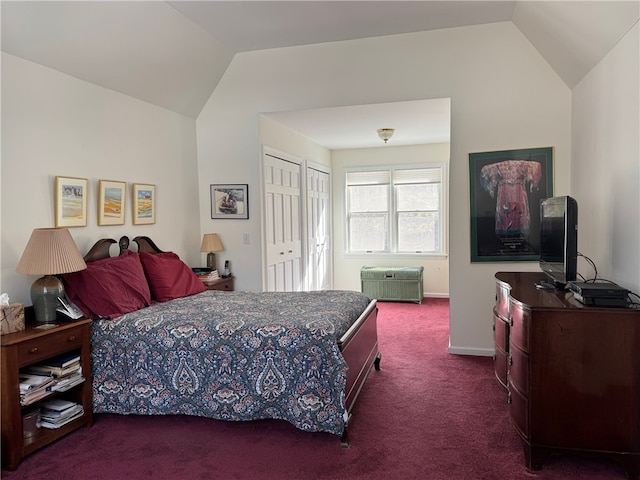 bedroom featuring lofted ceiling, a closet, baseboards, and dark colored carpet