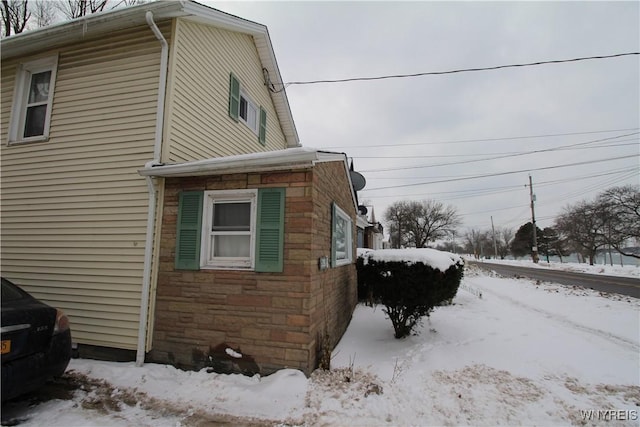 view of snowy exterior featuring stone siding