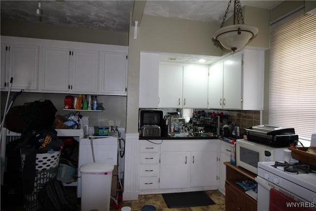 kitchen with white appliances, dark countertops, backsplash, and white cabinetry