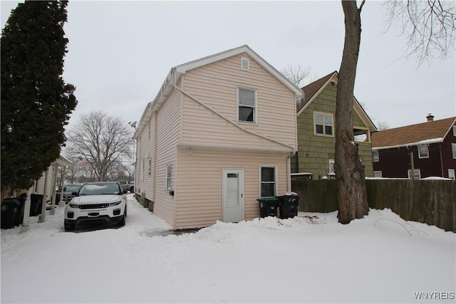 snow covered rear of property with fence