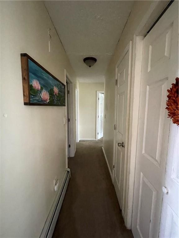 corridor with baseboard heating, carpet, and baseboards