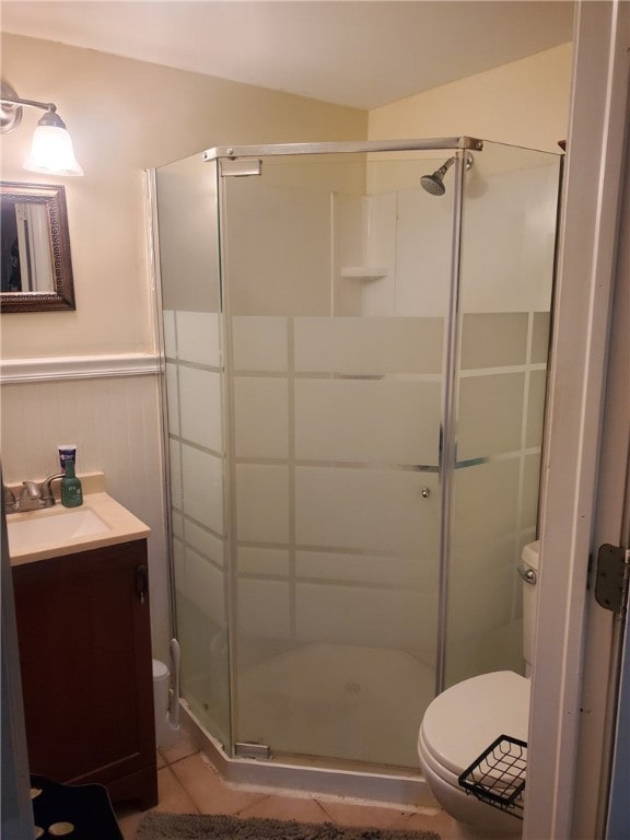 bathroom featuring a wainscoted wall, a stall shower, vanity, and toilet