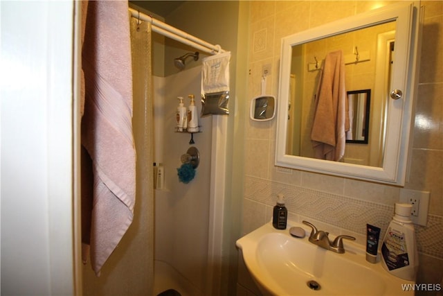 bathroom with a stall shower, backsplash, tile walls, and vanity