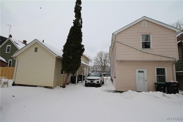 snow covered house featuring fence