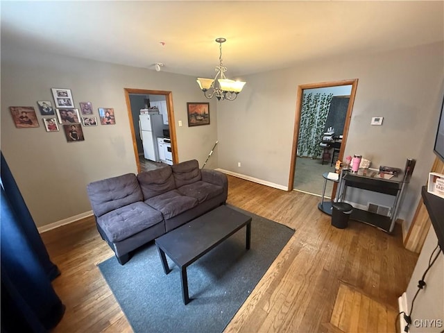 living area featuring a notable chandelier, baseboards, and wood finished floors