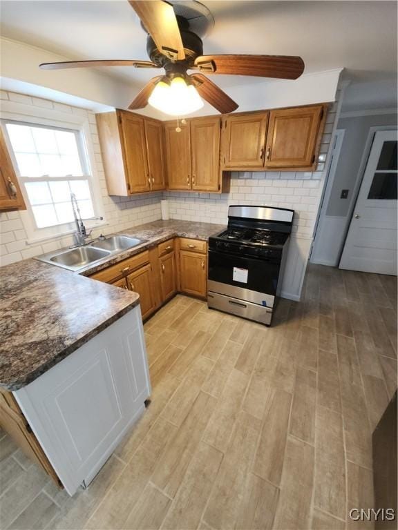 kitchen featuring tasteful backsplash, a sink, gas range, and light wood-style floors