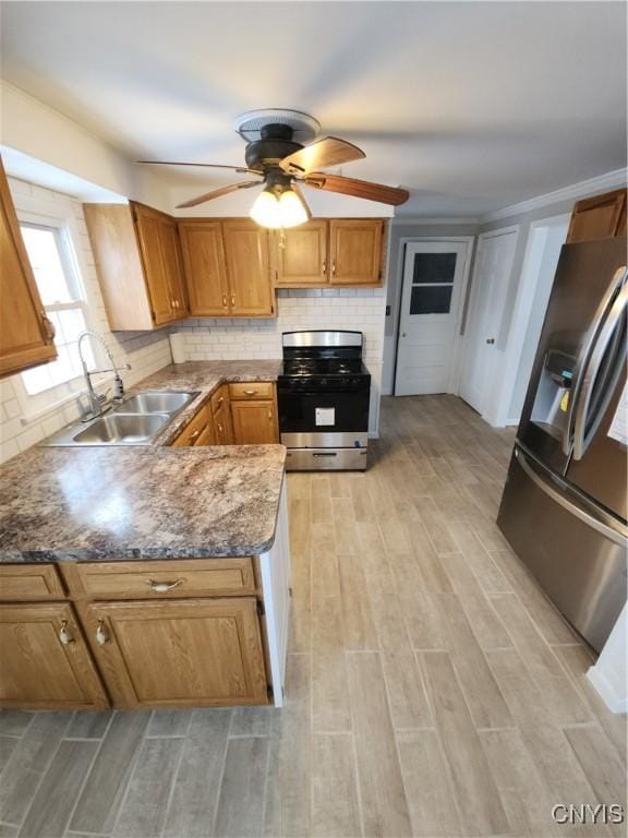 kitchen with a ceiling fan, a sink, stainless steel appliances, light wood-type flooring, and backsplash