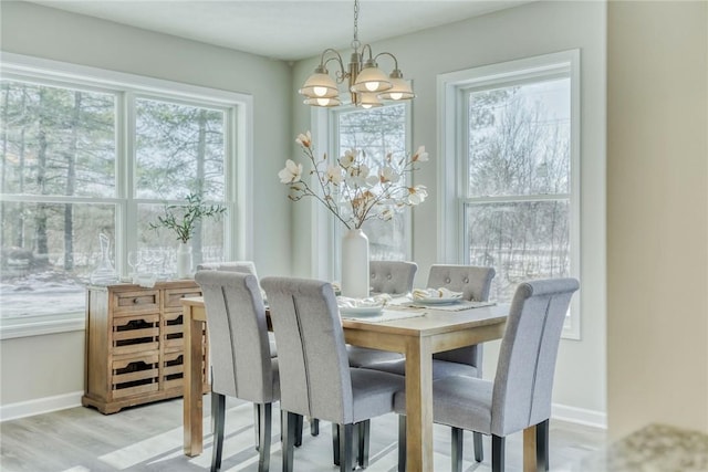 dining area featuring an inviting chandelier, wood finished floors, and baseboards