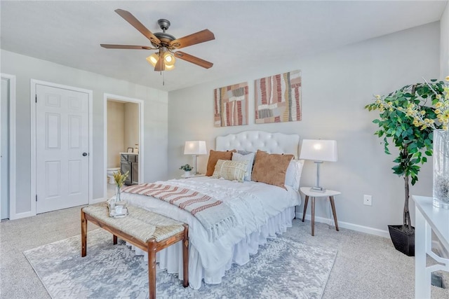 carpeted bedroom with ensuite bath, a ceiling fan, and baseboards