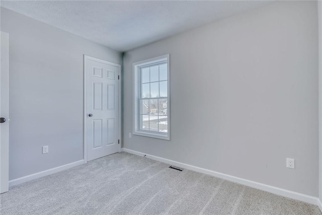 spare room featuring carpet, visible vents, a textured ceiling, and baseboards