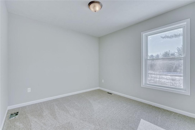 carpeted spare room featuring visible vents and baseboards