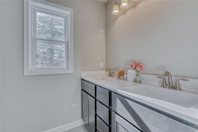 full bathroom featuring double vanity, baseboards, and a sink