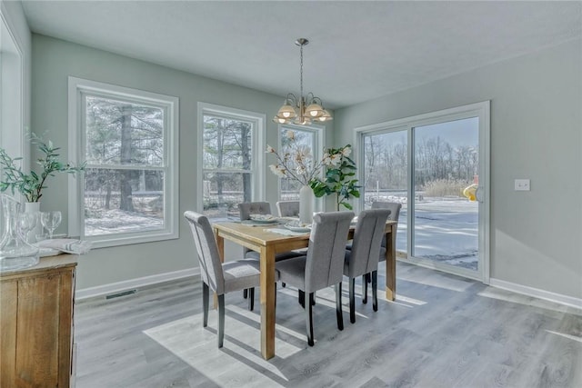 dining area with an inviting chandelier, light wood-style flooring, visible vents, and baseboards