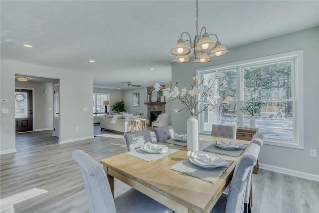 dining room with light wood-style flooring, a fireplace, baseboards, and recessed lighting