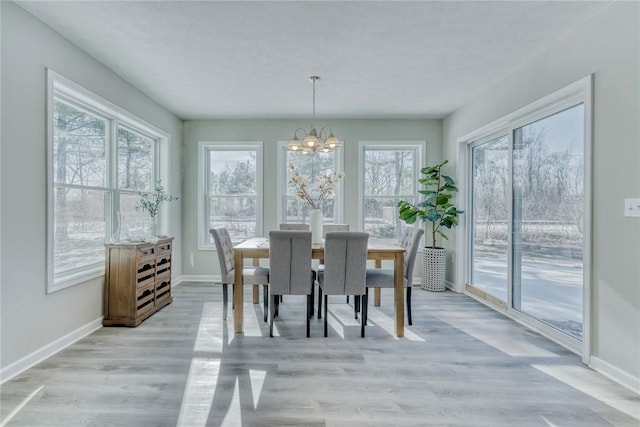 dining space featuring light wood finished floors, baseboards, and an inviting chandelier