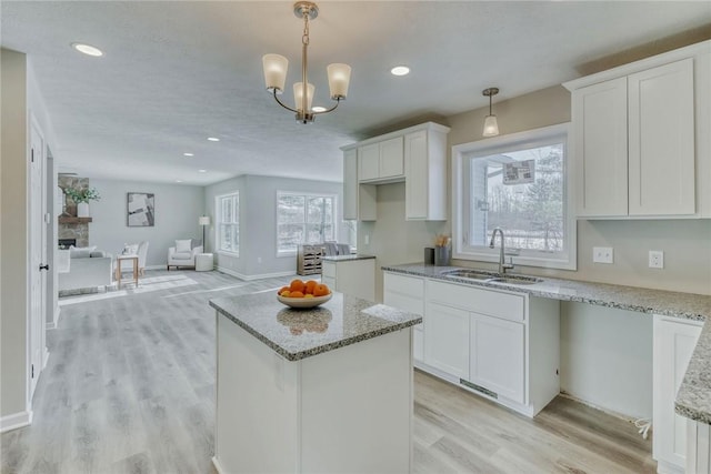 kitchen with a sink, light stone countertops, and white cabinets