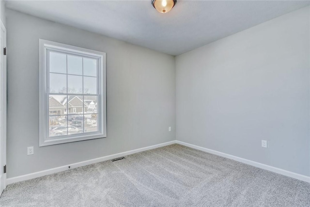 spare room with carpet, visible vents, and baseboards