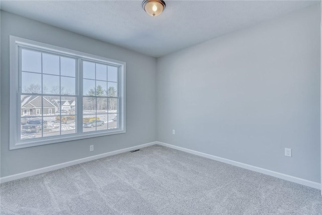 empty room with carpet flooring, visible vents, and baseboards