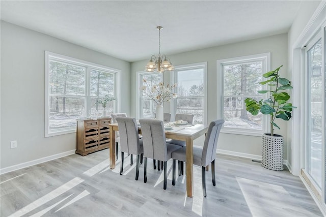 dining area featuring a notable chandelier, light wood-style flooring, and baseboards