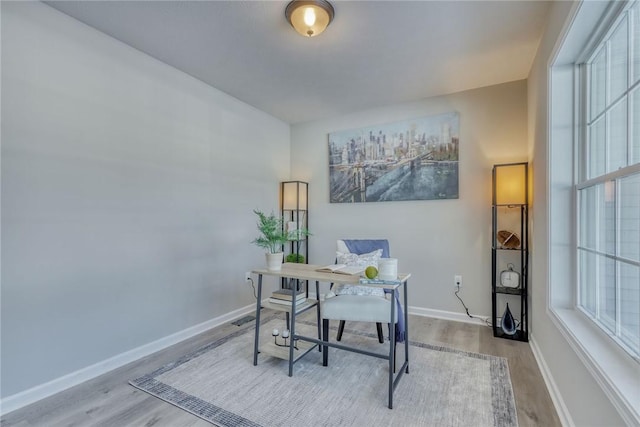 office area featuring baseboards, wood finished floors, and a healthy amount of sunlight