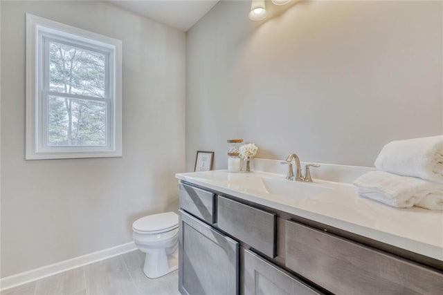 bathroom featuring vanity, toilet, and baseboards