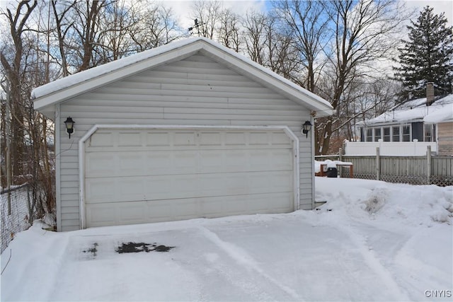 snow covered garage with a garage and fence