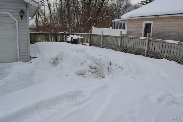 yard covered in snow with a garage and fence