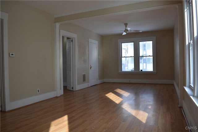 unfurnished room featuring a ceiling fan, wood finished floors, visible vents, and baseboards