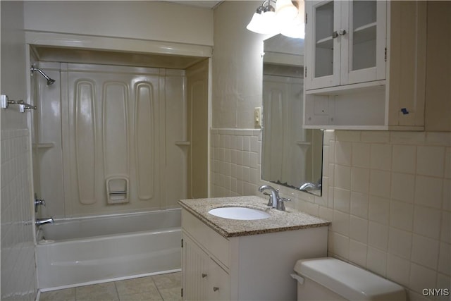 bathroom with tile walls, toilet, vanity,  shower combination, and tile patterned floors