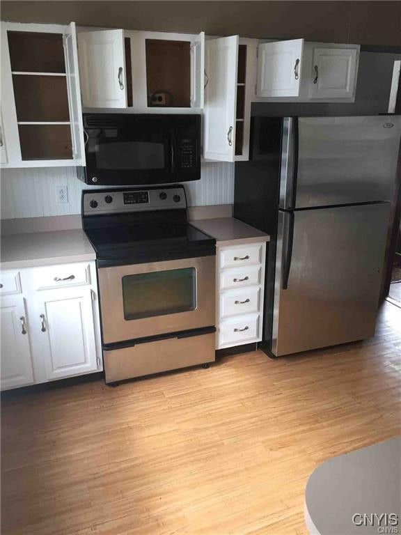 kitchen with open shelves, light wood finished floors, white cabinets, and stainless steel appliances