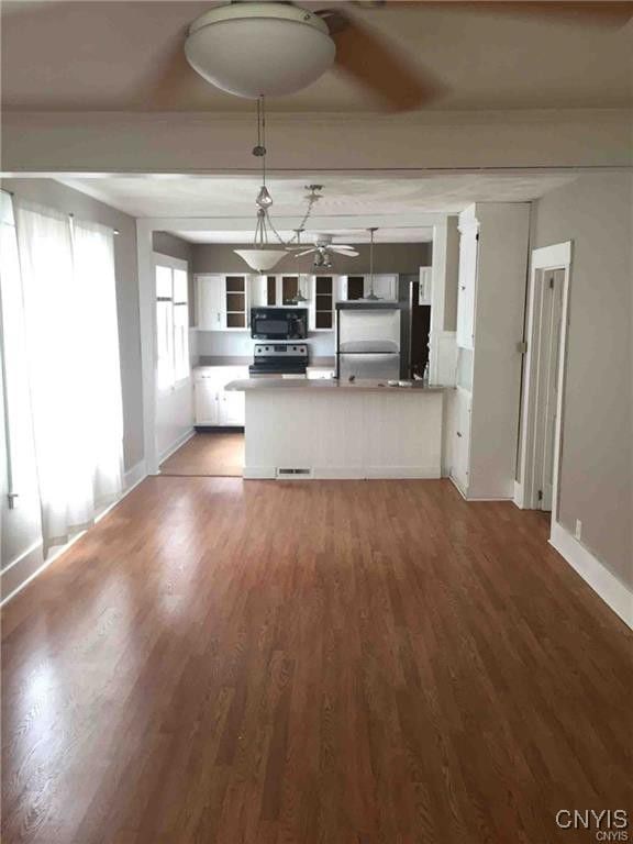 kitchen with appliances with stainless steel finishes, white cabinets, a peninsula, and wood finished floors