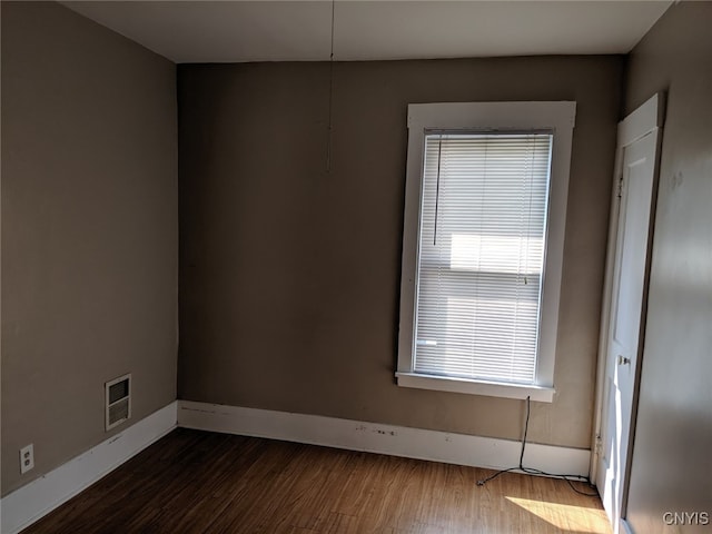 empty room featuring baseboards, visible vents, and dark wood-type flooring