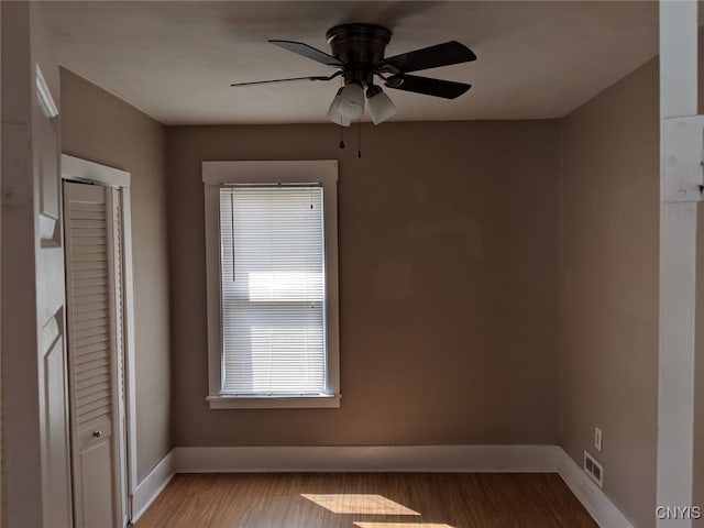 unfurnished room with ceiling fan, light wood-type flooring, visible vents, and baseboards