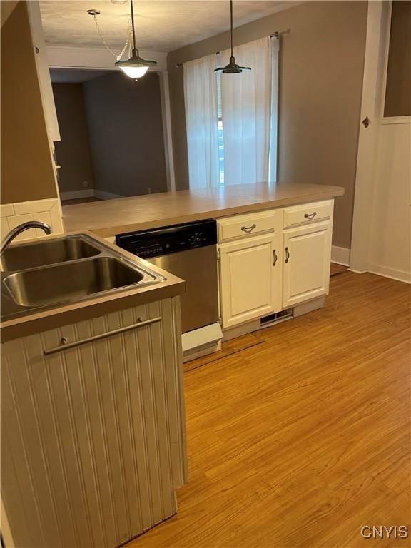 kitchen with a sink, light wood-style floors, white cabinets, dishwasher, and pendant lighting