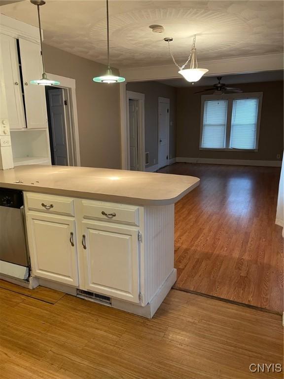 kitchen featuring light wood finished floors, light countertops, white cabinets, dishwasher, and a peninsula