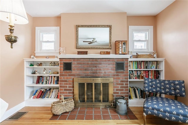 living area with a healthy amount of sunlight, visible vents, a fireplace, and wood finished floors