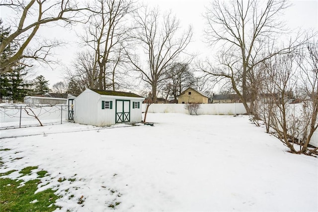 yard covered in snow with a storage shed, a fenced backyard, and an outdoor structure