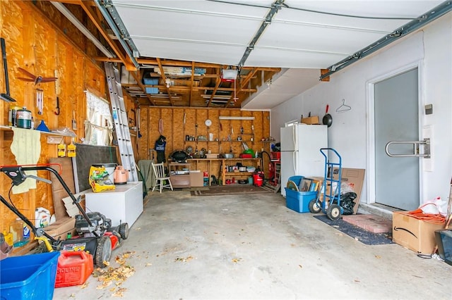 garage with a garage door opener, a workshop area, and freestanding refrigerator