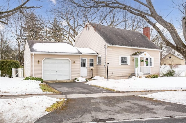 cape cod house with aphalt driveway, an attached garage, a shingled roof, fence, and a chimney