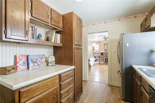 kitchen with wallpapered walls, light wood-style flooring, freestanding refrigerator, light countertops, and open shelves