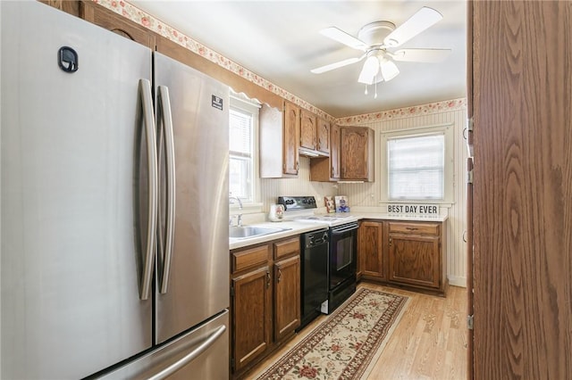 kitchen featuring plenty of natural light, dishwashing machine, freestanding refrigerator, black electric range, and a sink